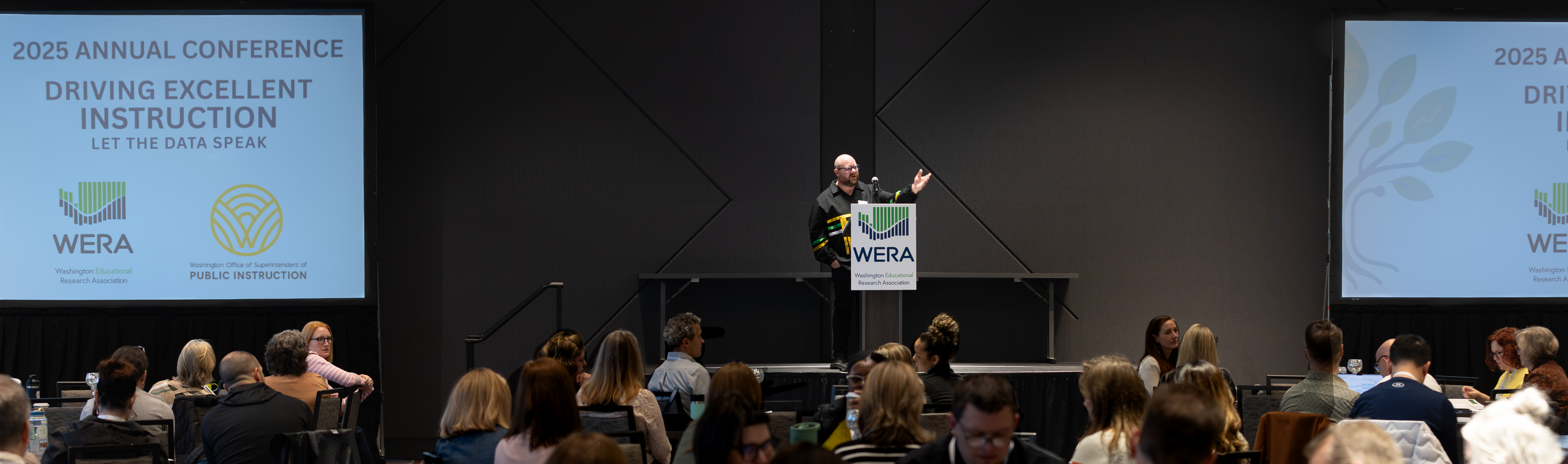 Dr. Kenneth Olden delivers the welcome address at the 2025 WERA conference. He is wearing a traditional Yakama ribbon shirt.